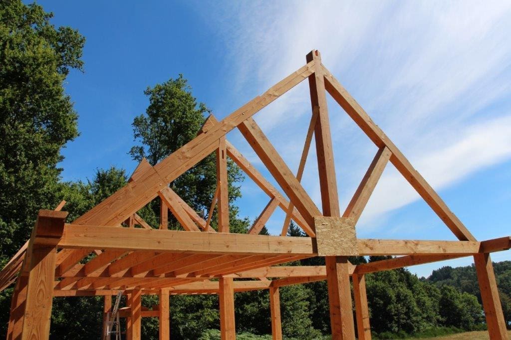 Oak roof truss under construction against a blue sky