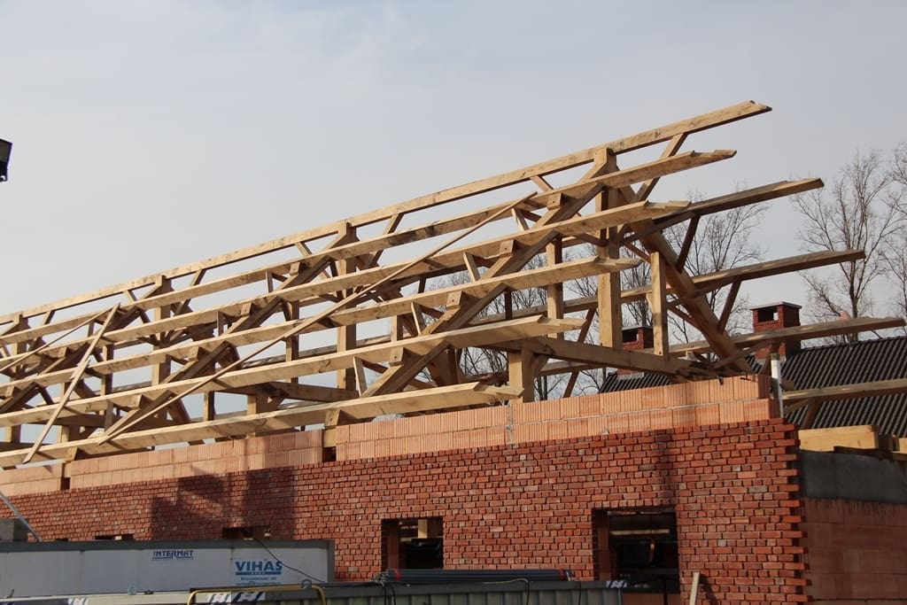 Customer project: oak truss being erected on a brick wall